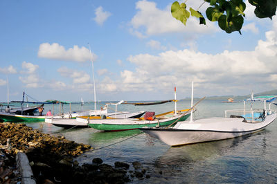 Sailboats moored in sea against sky