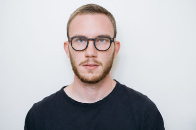 Portrait of young man wearing eyeglasses against white background