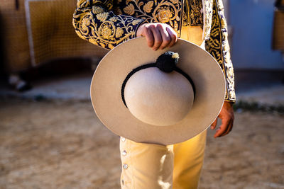 Crop unrecognizable bullfighter in traditional costume decorated with embroidery holding a hat preparing for corrida festival