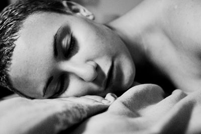 Close-up of young woman with short hair sleeping on bed at home