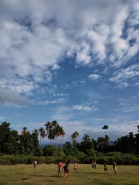 People playing on field against sky