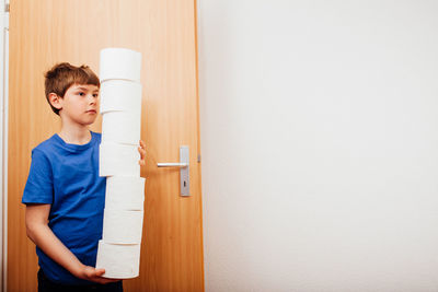 Boy looking away while standing against door