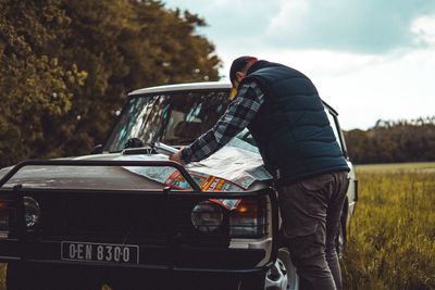 Side view of man standing by car