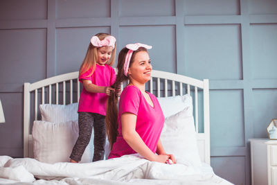 Full length of smiling woman standing on bed