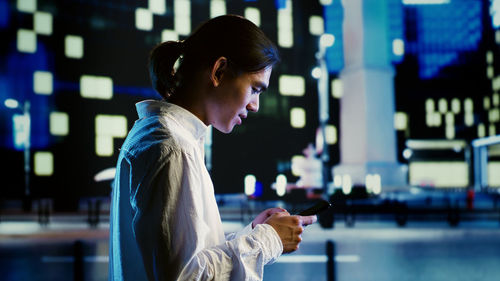 Side view of young woman using mobile phone