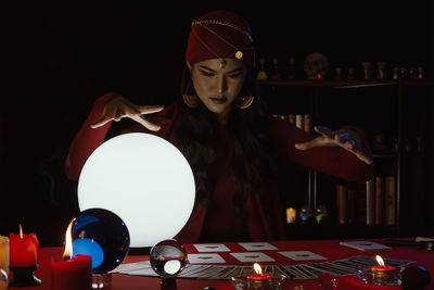 Female fortune teller with sphere and tarot cards at home