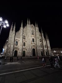 People at illuminated temple against sky at night