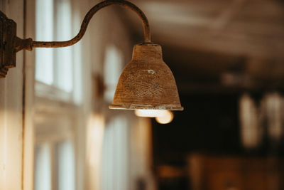 Close-up of electric lamp hanging against wall at home