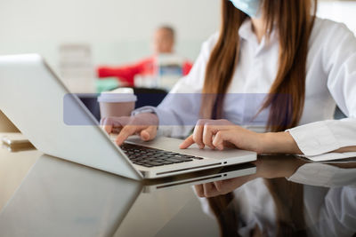 Midsection of woman using laptop at office