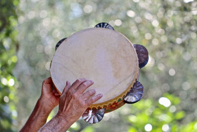 Cropped hand of man holding tambourine outdoors