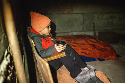 Ukrainian girl sits in bomb shelter, drinks tea and waits for end of airstrike of russian invaders