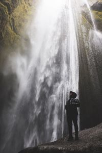 Rear view of man standing by waterfall