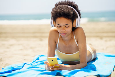 Young woman listening music at beach
