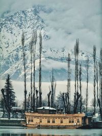 Built structure by trees against sky during winter