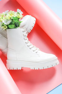 White demi-season boots made of eco-leather on a rough sole with lacing and a  flowers.