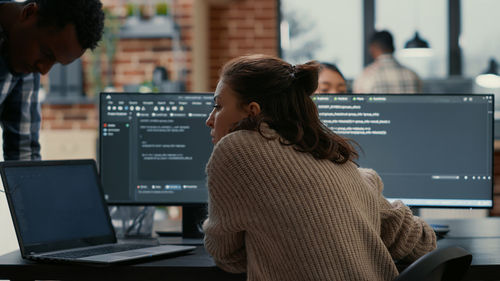 Rear view of businesswoman talking with colleague at office