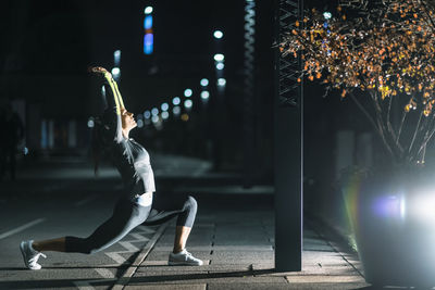 Woman exercising in city at night