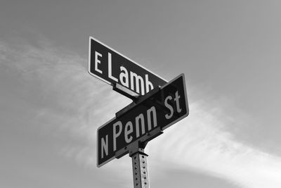 Low angle view of road sign against sky in black and white