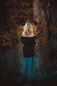 Rear view of woman standing in forest