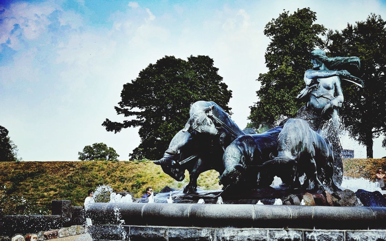 sculpture, statue, human representation, art and craft, art, creativity, tree, low angle view, sky, blue, fountain, animal representation, water, day, no people, park - man made space, outdoors, nature