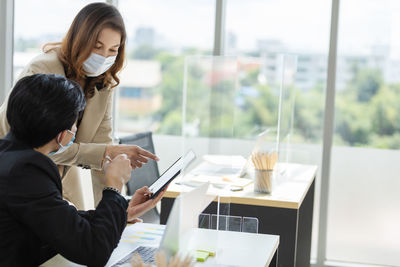 Business persons wearing mask using digital tablet brainstorming in office