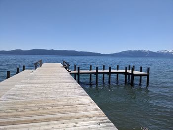 Pier over sea against clear blue sky