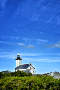 Lighthouse amidst trees and buildings against sky