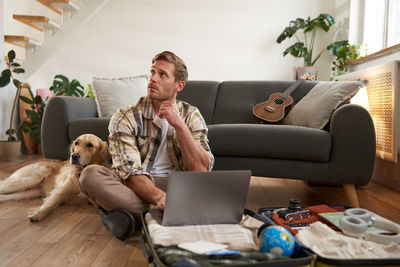 Young woman using laptop while sitting on sofa at home