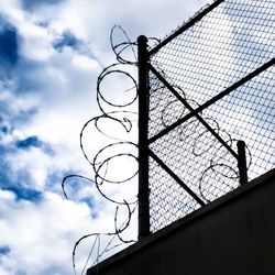 Low angle view of chainlink fence against sky