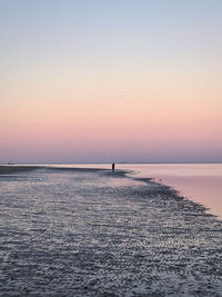 Silhouette person on sea against clear sky during sunset