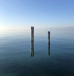 Wooden post in lake against sky