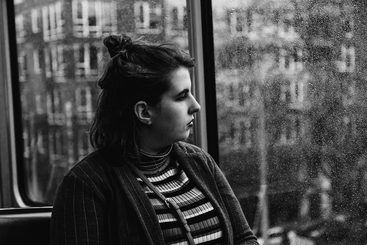 PORTRAIT OF YOUNG WOMAN LOOKING AWAY WHILE WINDOW