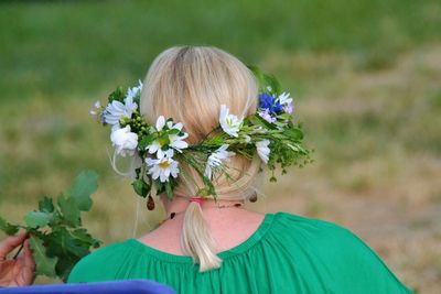 Rear view of woman with flowers against blurred background