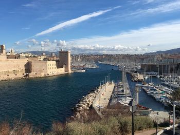 Boats moored at harbor against sky