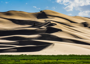 Scenic view of sand dune on field against sky