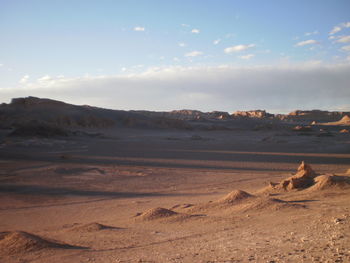 Scenic view of desert against cloudy sky