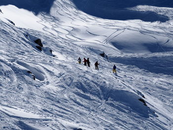 Mid distant view of people at snow covered landscape during winter