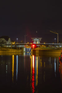 River by illuminated city against sky at night