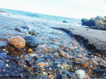 Close-up of pebbles on beach against sky