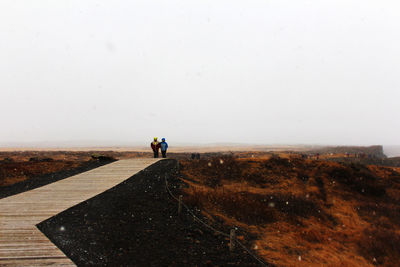 People walking on a snowy day on a bridge in iceland