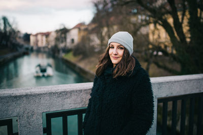 Portrait of woman standing on bridge over canal in city