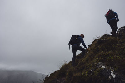 Low angle view of men climbing on cliff