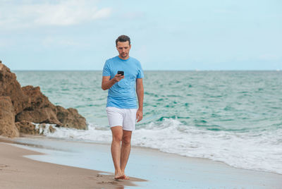 Portrait of man standing at beach against sky