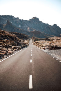 Empty road along landscape and mountains against sky