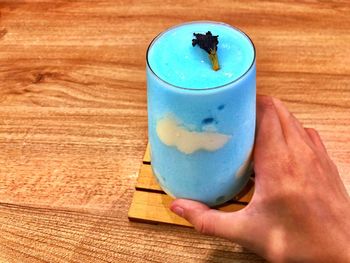 Close-up of person hand holding drink on table