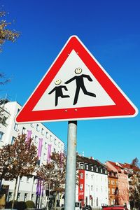 Low angle view of road sign against clear blue sky