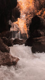 Scenic view of waterfall by rocks at shore