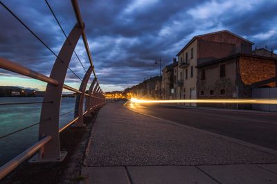 Illuminated bridge over road against sky in city