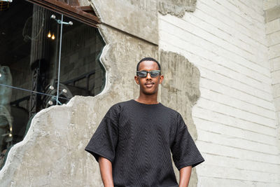 Portrait of young man standing against wall