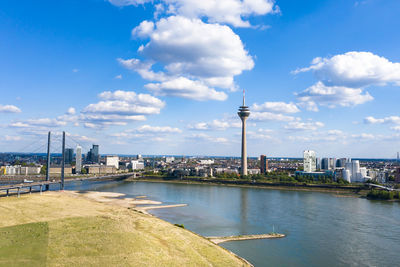 View of buildings by river against cloudy sky